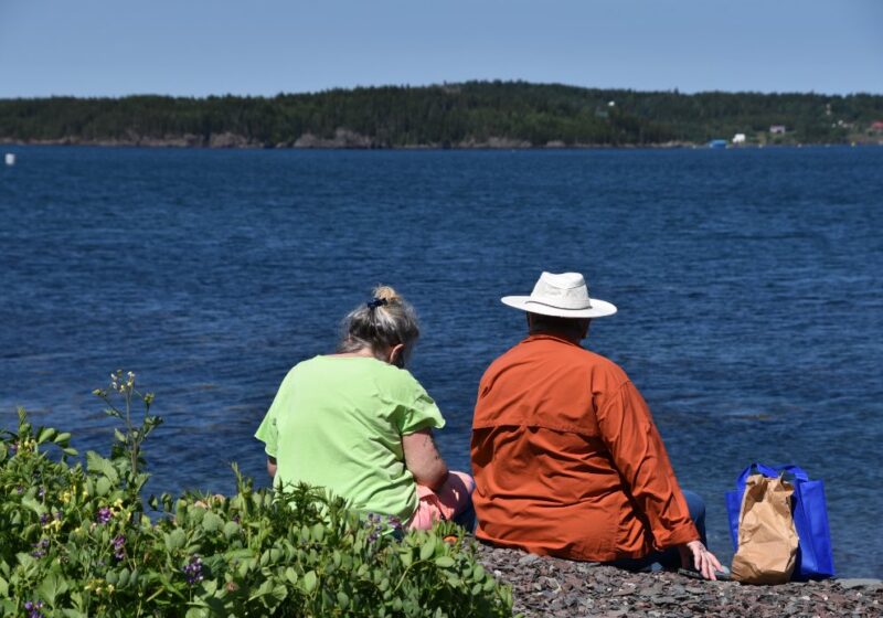 Two community members sitting together looking out over the water